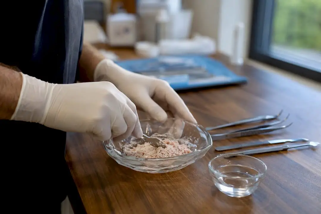 Hands mixing bone graft in surgical bowl
