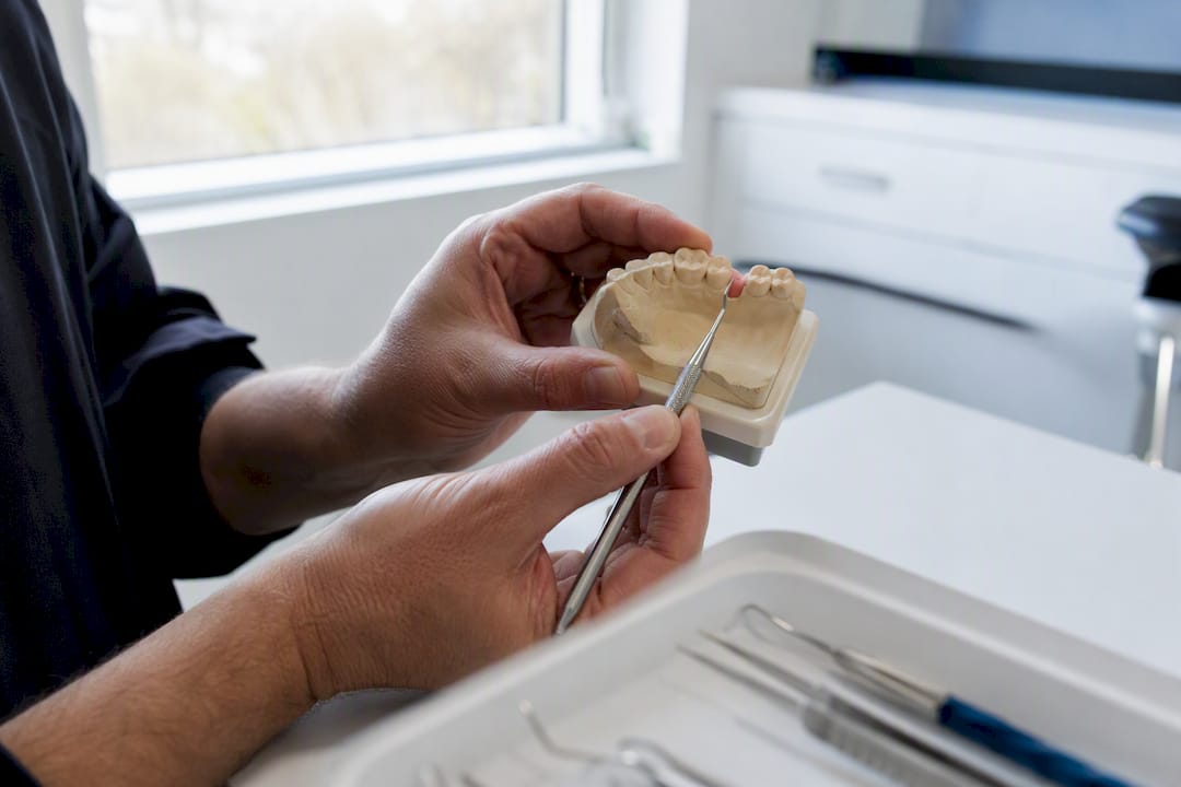 Hands palpating premolar implant site on dental cast