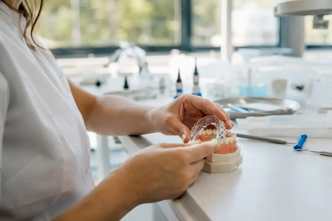 Hands placing indirect bonding tray on dental model